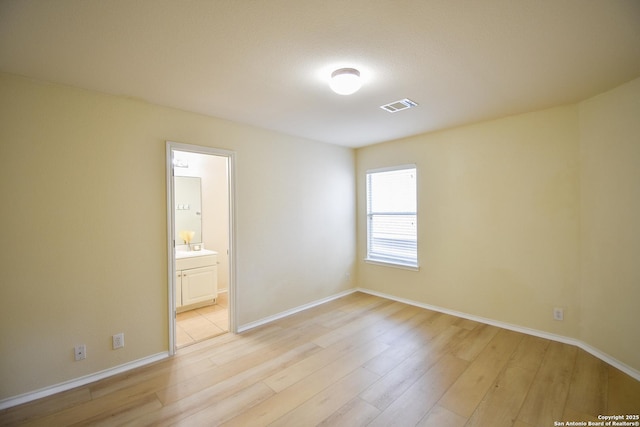 spare room with light wood-style floors, baseboards, and visible vents