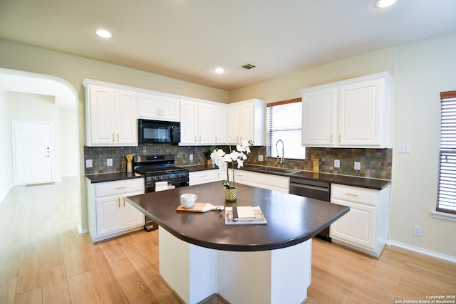 kitchen with stainless steel appliances, a sink, visible vents, white cabinetry, and dark countertops