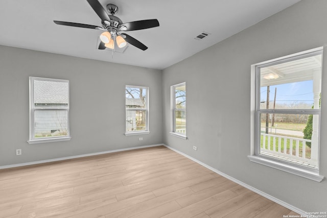 empty room featuring a ceiling fan, visible vents, light wood-style flooring, and baseboards