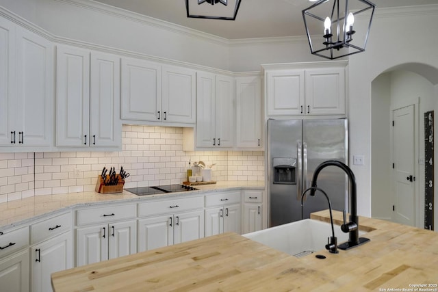 kitchen with butcher block countertops, white cabinetry, crown molding, and stainless steel refrigerator with ice dispenser