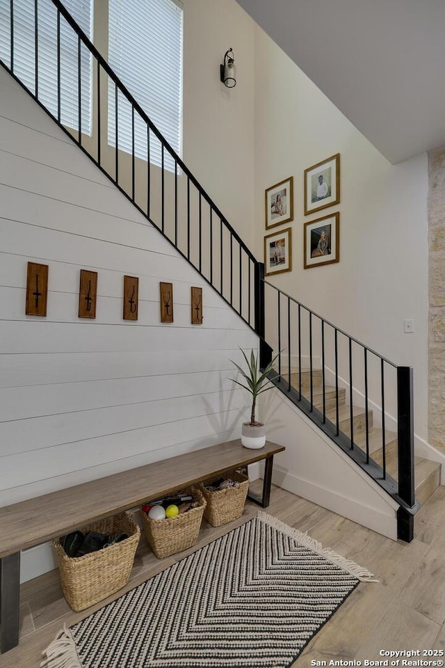 stairway with a towering ceiling, baseboards, and wood finished floors