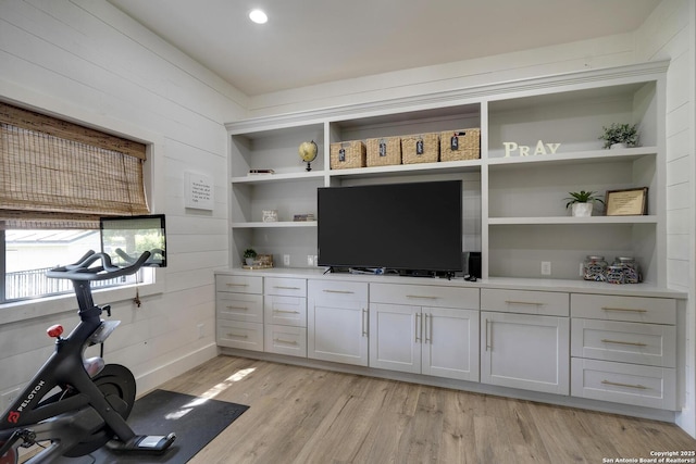 workout area featuring light wood-type flooring, wooden walls, and built in features