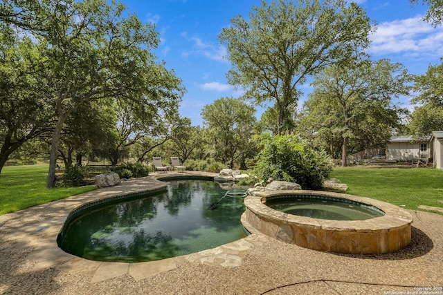 view of pool with a yard and a pool with connected hot tub