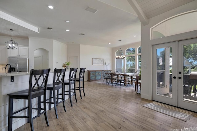 interior space featuring a breakfast bar area, stainless steel fridge, light wood-style flooring, and a notable chandelier