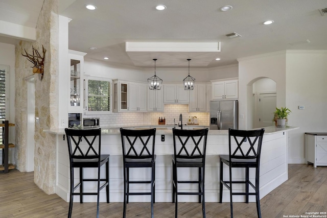 kitchen with white cabinets, a breakfast bar area, stainless steel appliances, and backsplash