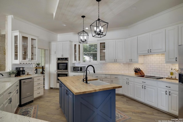 kitchen with butcher block counters, appliances with stainless steel finishes, white cabinets, and a sink