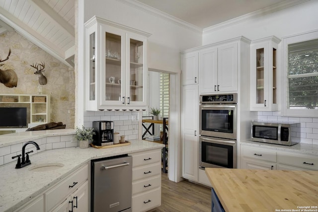 kitchen with stainless steel appliances, white cabinets, a sink, and tasteful backsplash