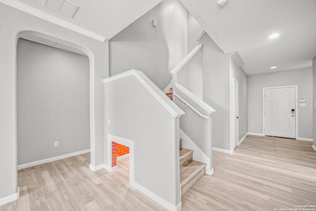 stairway featuring a textured ceiling, recessed lighting, wood finished floors, and baseboards