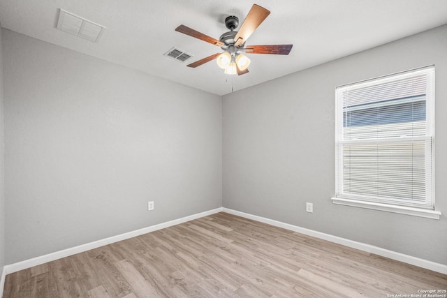 spare room with light wood-type flooring, visible vents, and baseboards