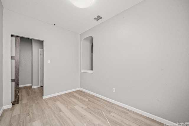 unfurnished room with baseboards, visible vents, and light wood finished floors