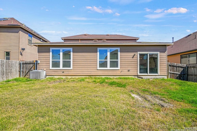 rear view of house with a fenced backyard, central AC, and a lawn