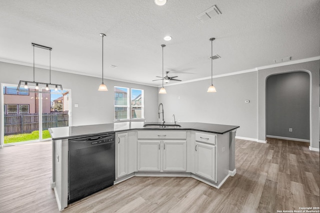 kitchen with white cabinets, dishwasher, dark countertops, a kitchen island with sink, and a sink