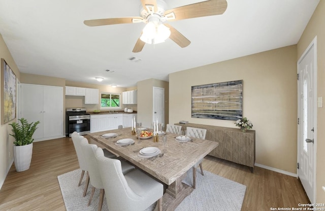 dining area with light wood-type flooring, visible vents, and baseboards