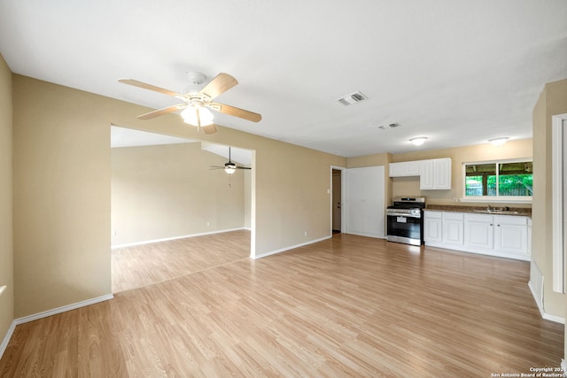 unfurnished living room with light wood-style floors, baseboards, visible vents, and a sink