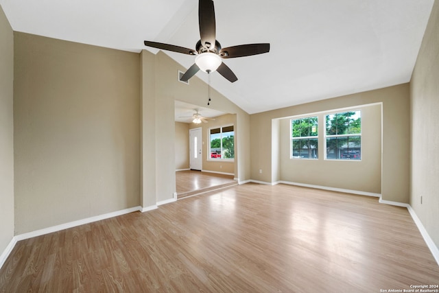 empty room with light wood-style floors, vaulted ceiling, and baseboards