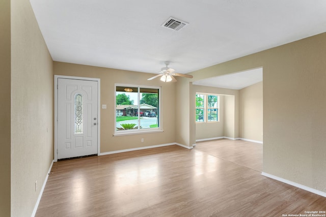 interior space featuring baseboards, visible vents, ceiling fan, and light wood finished floors