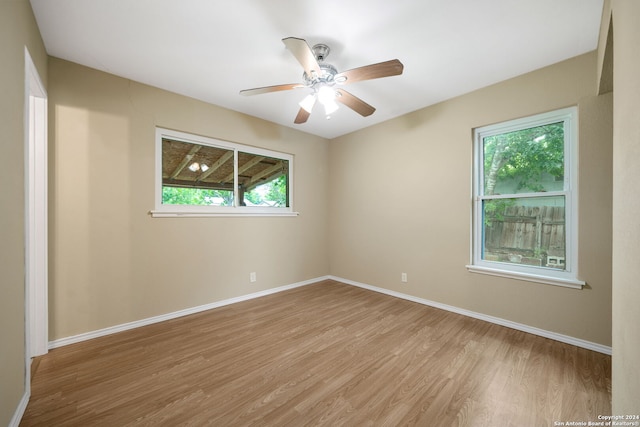 empty room featuring light wood-type flooring, a ceiling fan, and baseboards