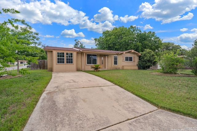 ranch-style home featuring a front yard, brick siding, fence, and driveway