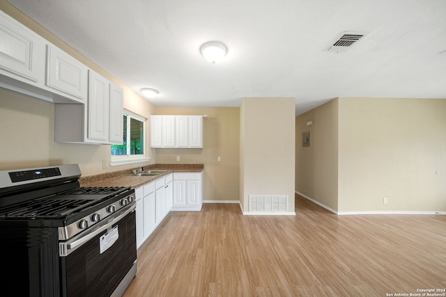 kitchen with stainless steel gas stove, visible vents, a sink, and white cabinetry