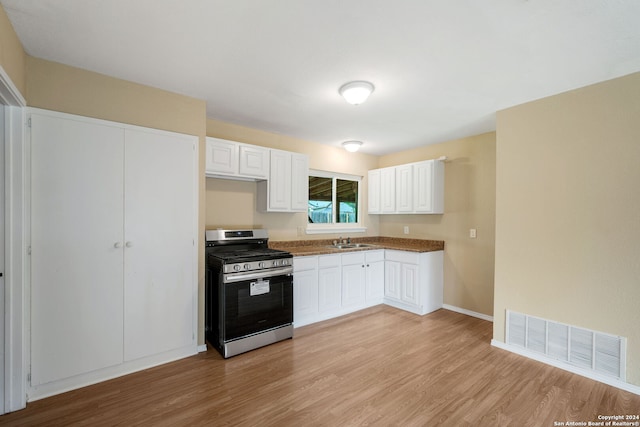 kitchen featuring visible vents, light wood-style flooring, white cabinetry, a sink, and stainless steel gas range oven