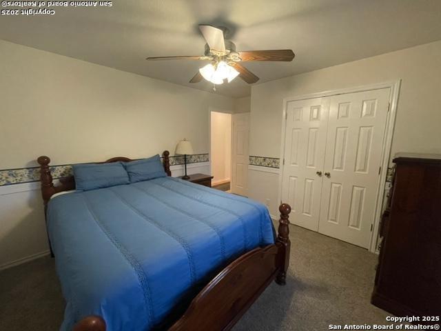 bedroom with a closet, dark carpet, and ceiling fan