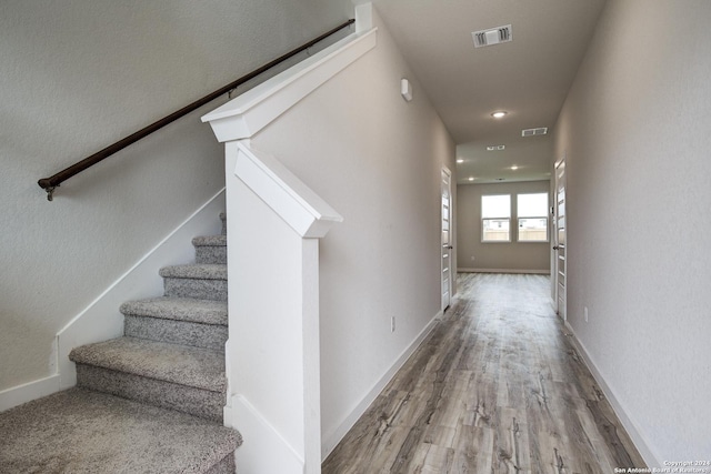 corridor with stairs, visible vents, baseboards, and wood finished floors