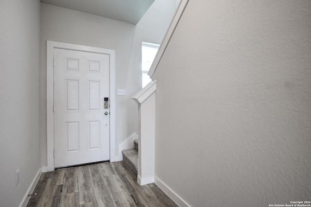 doorway with stairway, light wood-style flooring, and baseboards