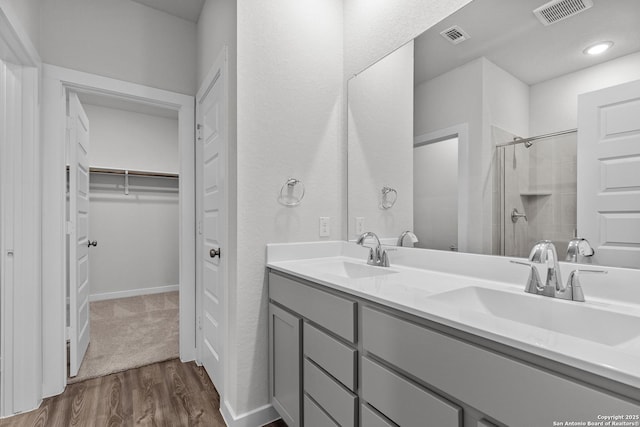 bathroom featuring a stall shower, a sink, visible vents, and a walk in closet