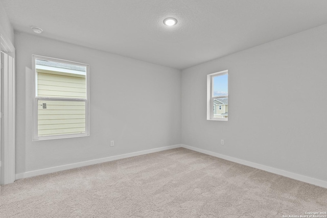 carpeted empty room featuring a textured ceiling and baseboards