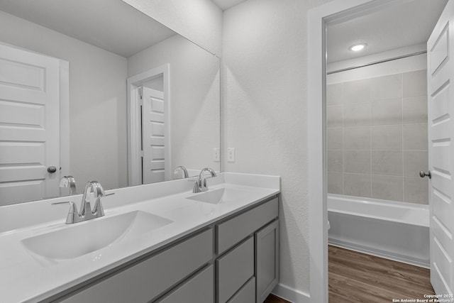 full bathroom with shower / bathtub combination, double vanity, wood finished floors, and a sink