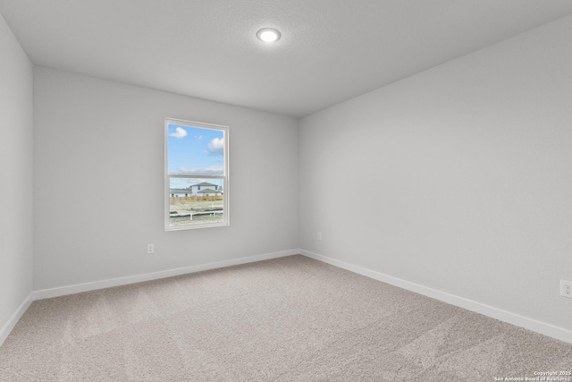 spare room featuring a textured ceiling, carpet flooring, and baseboards