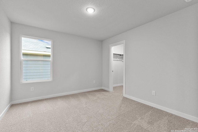 spare room featuring carpet flooring, a textured ceiling, and baseboards