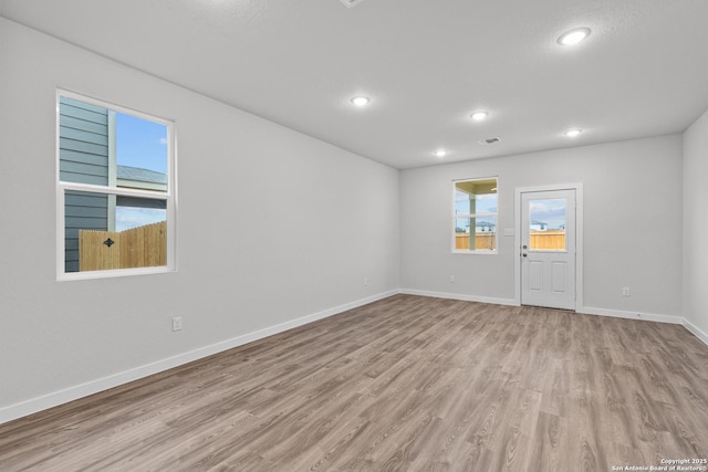 unfurnished room with light wood finished floors, visible vents, baseboards, and recessed lighting