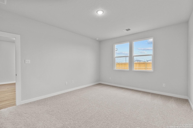 spare room featuring carpet flooring, visible vents, and baseboards