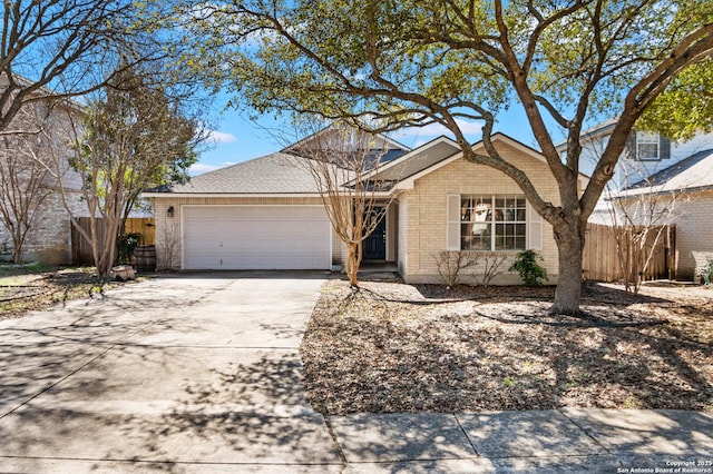 single story home featuring driveway, brick siding, an attached garage, and fence