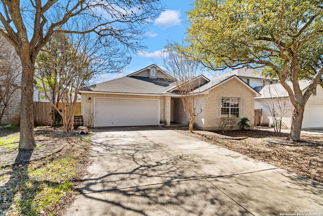 single story home with a garage, concrete driveway, brick siding, and fence