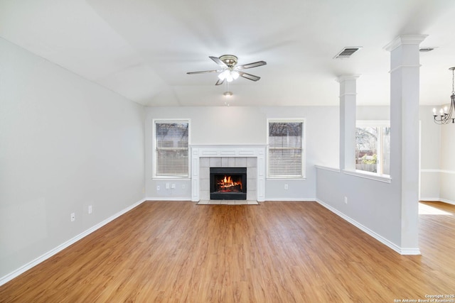 unfurnished living room featuring baseboards, light wood-style flooring, ornate columns, and ceiling fan with notable chandelier