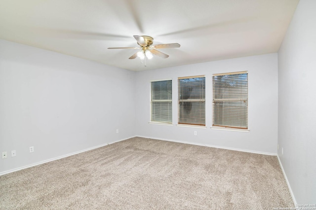 carpeted spare room with a ceiling fan and baseboards