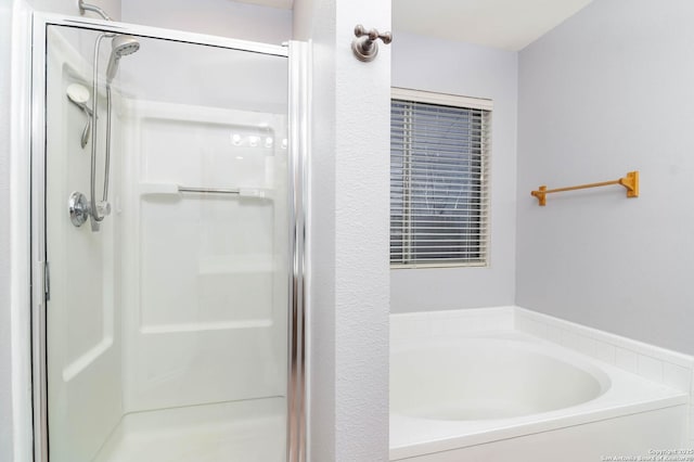 bathroom with a stall shower and a garden tub