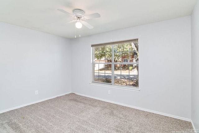 carpeted empty room featuring ceiling fan and baseboards