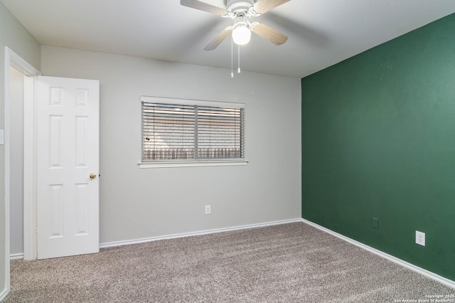 spare room with carpet floors, ceiling fan, and baseboards