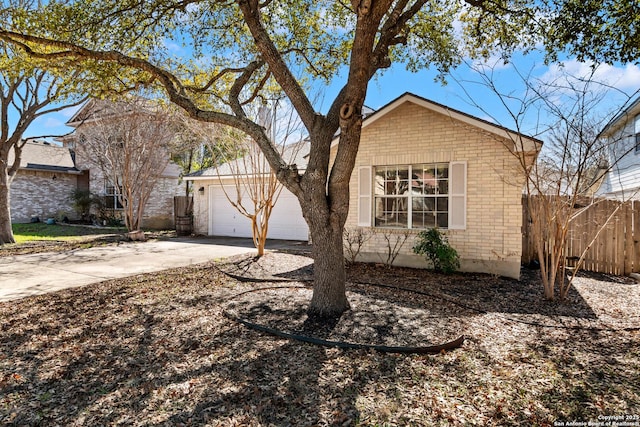 view of front facade featuring driveway, brick siding, an attached garage, and fence