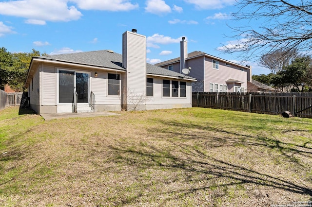 back of house with a yard, a shingled roof, a chimney, and a fenced backyard