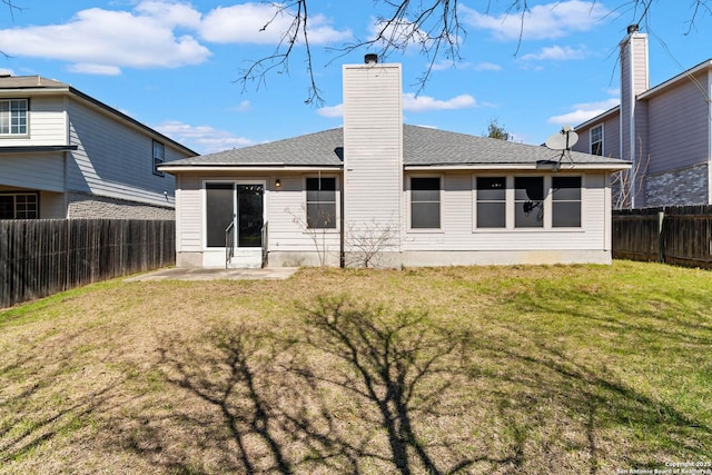 back of house with a yard, a chimney, and a fenced backyard