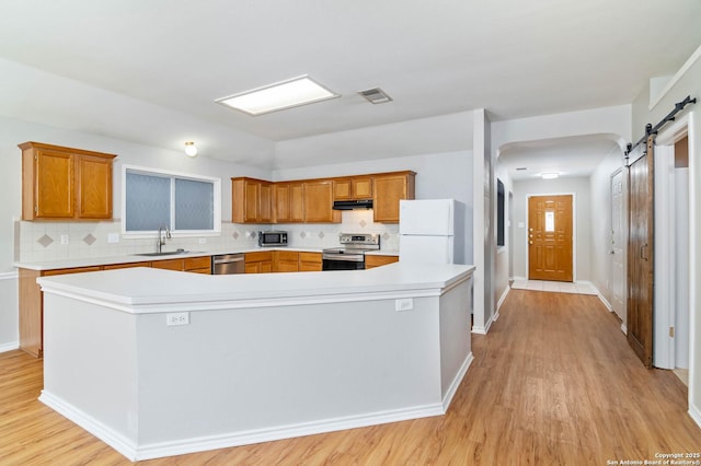 kitchen with a barn door, stainless steel appliances, light countertops, and a center island