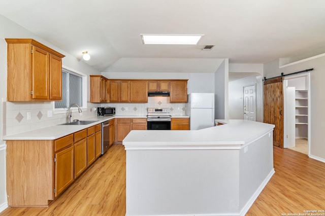 kitchen featuring stainless steel appliances, light countertops, a sink, and a barn door