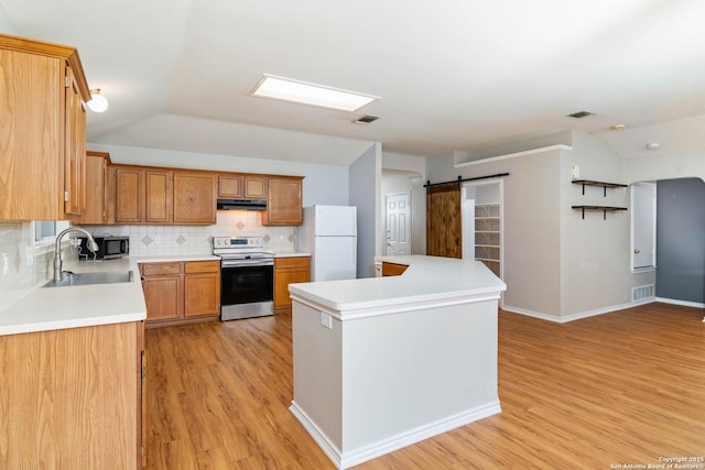 kitchen featuring light countertops, visible vents, a barn door, appliances with stainless steel finishes, and a sink