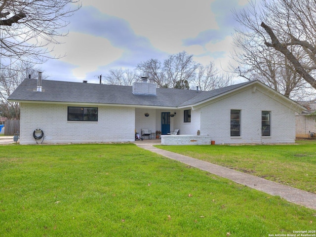 single story home with brick siding, a chimney, and a front lawn