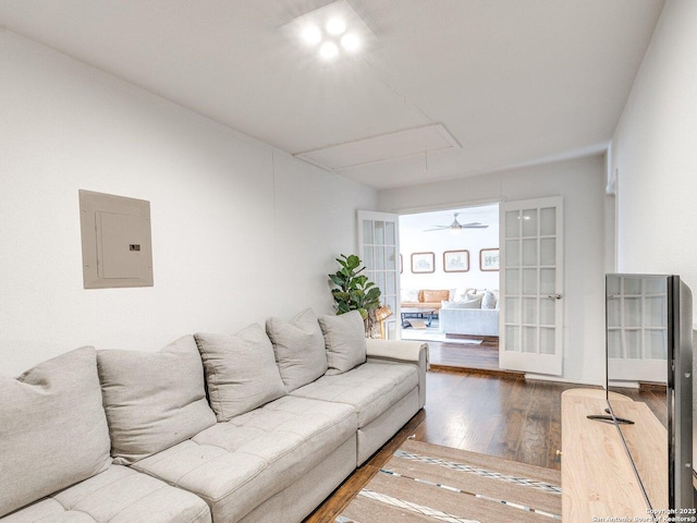 living area with attic access, electric panel, and wood finished floors