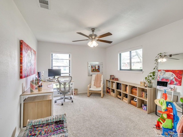 carpeted office featuring plenty of natural light, visible vents, ceiling fan, and a textured ceiling